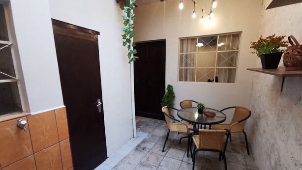 A small, enclosed outdoor area with a round table and chairs, a potted plant, and a window with a view. - Beautiful apartment in the city center (Arequipa)