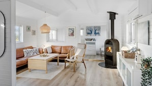 A cozy living room with a fireplace, a sofa, a coffee table, and a chair. - Pet friendly home in Bogø By with WiFi (Bogø By)