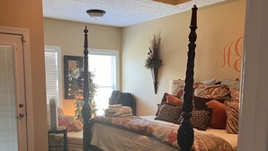 Une chambre à coucher avec un lit à baldaquin, une décoration murale et une grande fenêtre avec des stores.