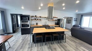 A modern kitchen with a central island, built-in appliances, and a seating area with a sofa and chairs. - Up North Luxury w/Unmatched Charm! 2 miles to MTU! (Hancock)