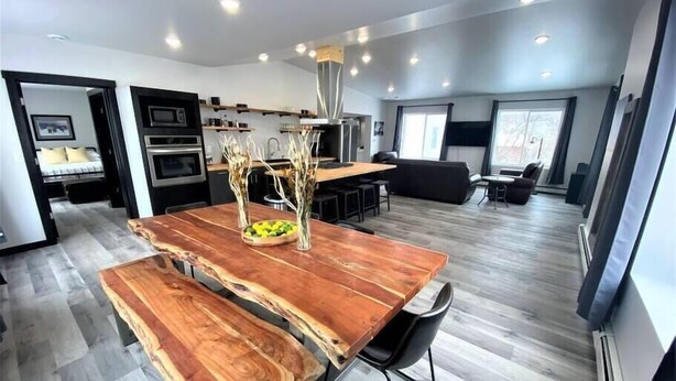 A modern kitchen with a wooden dining table, built-in oven, and a seating area with a sofa and chairs. - Up North Luxury w/Unmatched Charm! 2 miles to MTU! (Hancock)