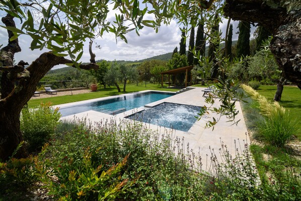A swimming pool with a pergola and a view of the countryside.