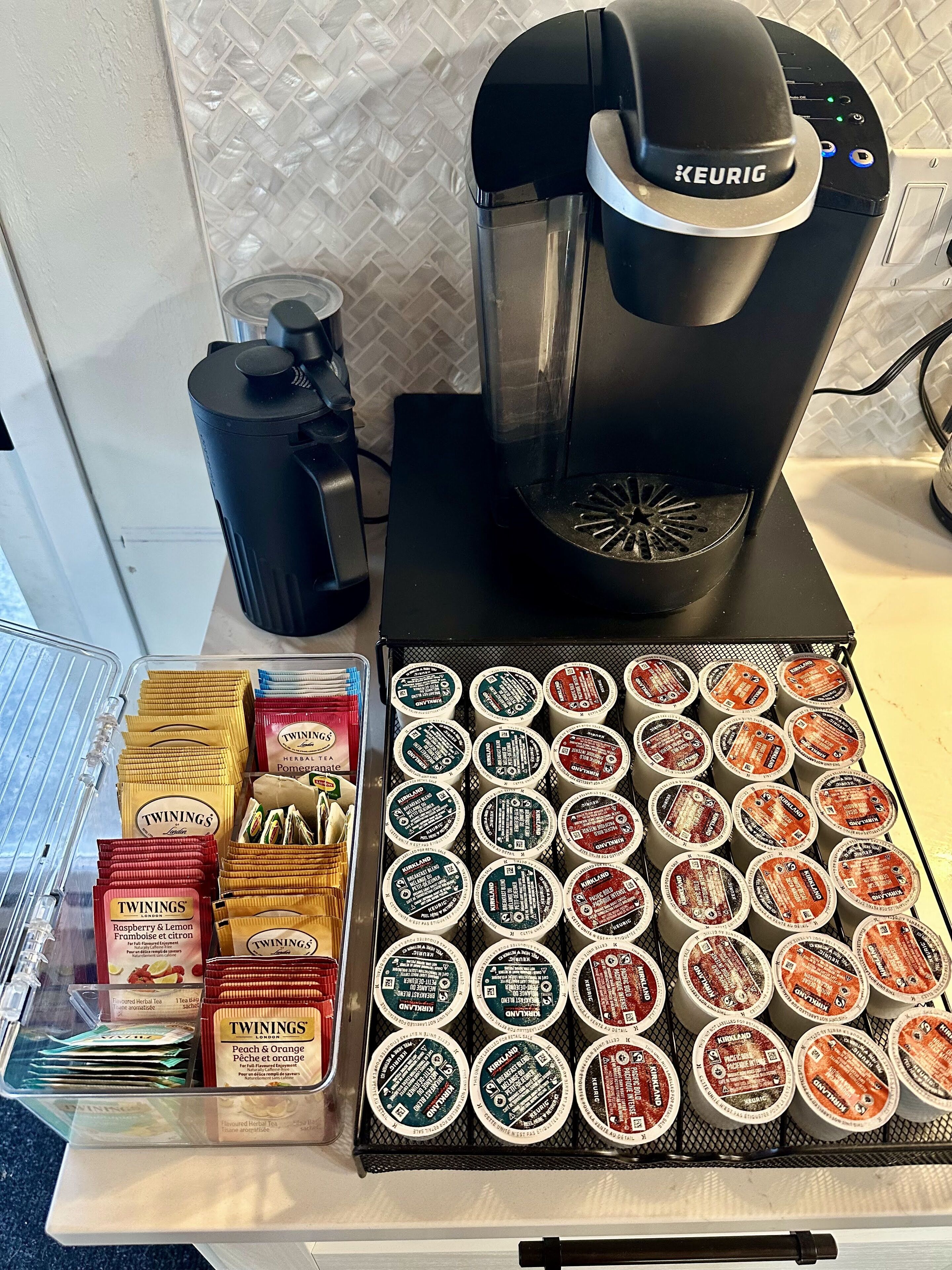 Een koffieapparaat, een waterdispenser, en een presentatie van Twinings theezakjes en capsules.