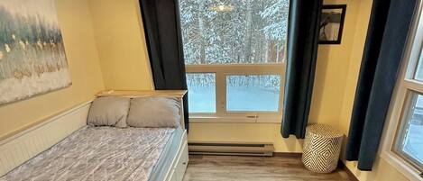 Un dormitorio con una cama, una ventana con cortinas, un cuadro en la pared y techo de madera.