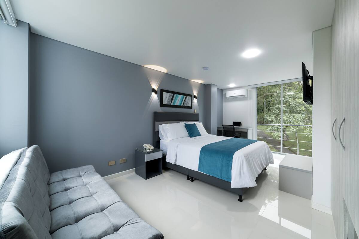 Un dormitorio moderno con cama, mesita de noche y sofá.