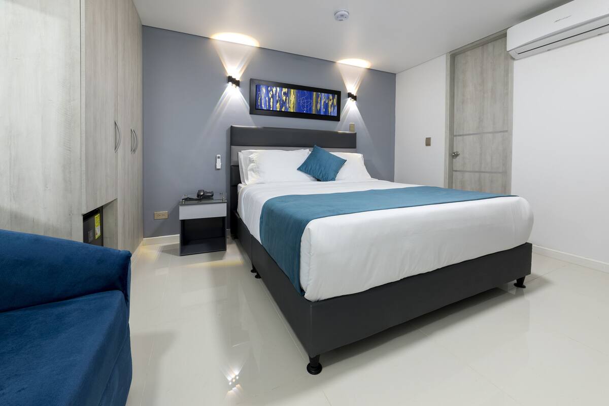 Un dormitorio moderno con cama, mesitas de noche y un sofá azul.