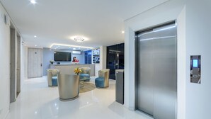 Un moderno vestíbulo de hotel con mostrador de recepción, zona de estar y ascensor.