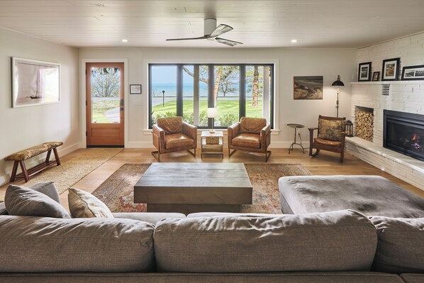 A living room with a large window, a fireplace, and a view of the outdoors.