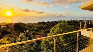 Vista panorámica desde un balcón con vistas a un paisaje costero al atardecer.