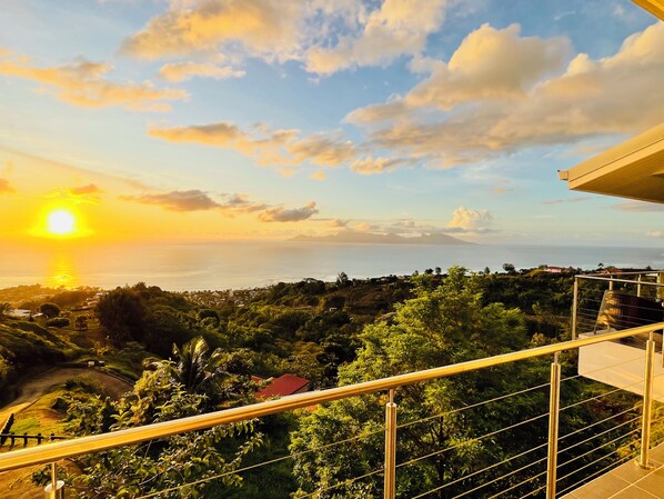 Vista panorámica desde un balcón con vistas a un paisaje costero al atardecer.