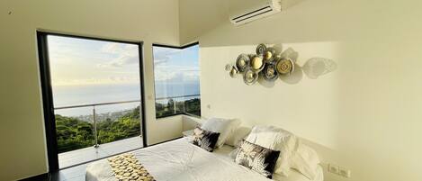 Un dormitorio con una cama grande, vista al mar y un elemento decorativo en la pared.