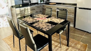 Una cocina moderna con comedor. Incluye una isla de cocina con estufa integrada, un refrigerador y una cafetera.