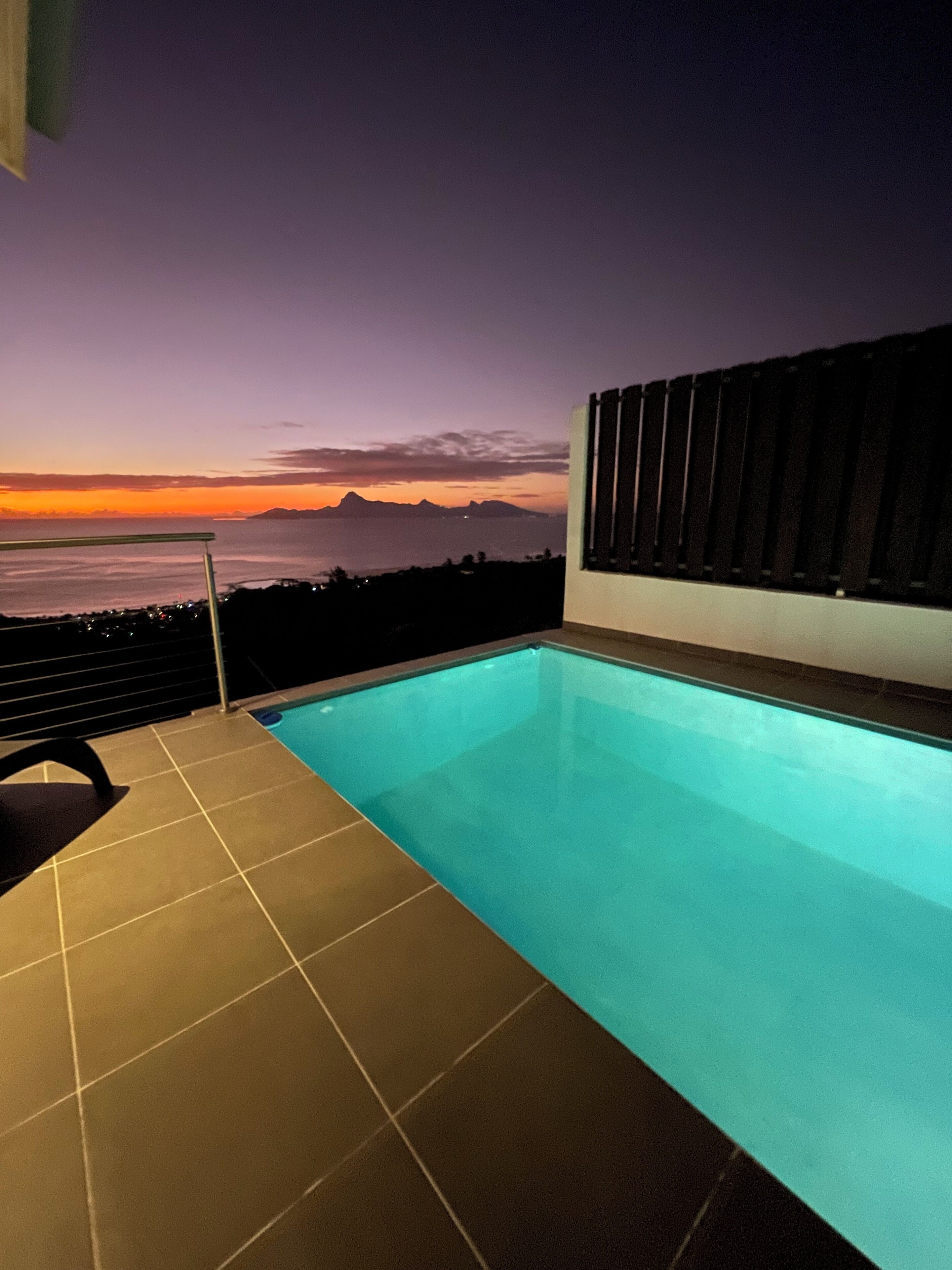 Una piscina con vista al océano al atardecer.