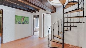 A spiral staircase with wooden steps and black metal railings, leading to an upper floor. - Casa Estufa 25 (Funchal)