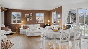 Una sala de estar acogedora con un sofá blanco, una mesa de comedor con sillas blancas y una chimenea.