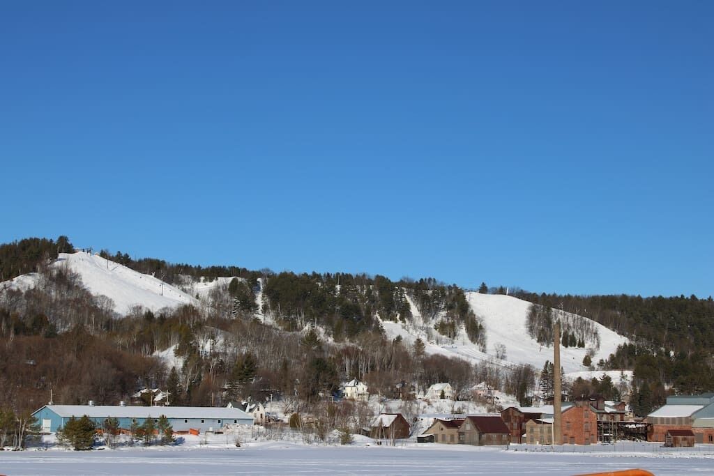 Une petite ville avec des bâtiments et une colline enneigée en arrière-plan.
