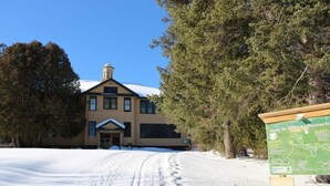 A building with a snow-covered path leading to its entrance, surrounded by trees. - Couples Getaway & Business Travel- 6 Miles to MTU (Chassell)