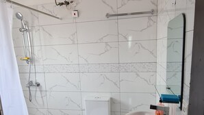 Uma casa de banho com chuveiro, sanita e lavatório.