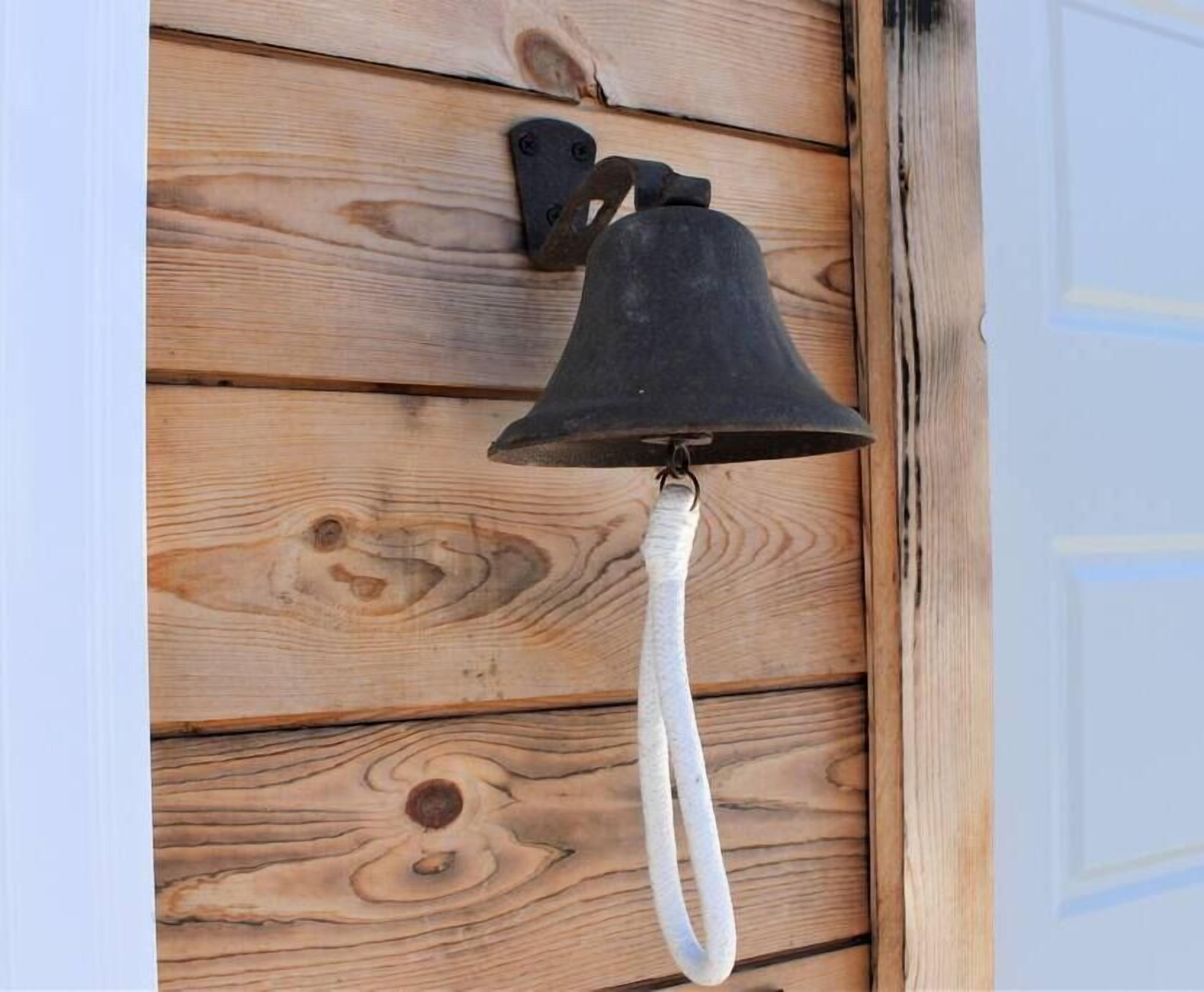Eine schwarze Außenglocke, die an einer Holzverkleidung mit weißem Seil befestigt ist.