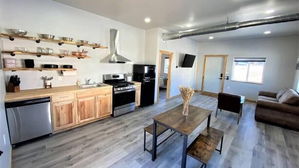 Une cuisine moderne avec des meubles en bois, des appareils en acier inoxydable et un coin repas comprenant une table et un banc en bois.
