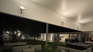 Una sala de estar moderna con un sofá seccional, una mesa de centro y un amplio ventanal con vista a un jardín.
