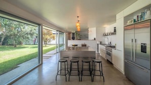 Una cocina moderna con una isla grande, electrodomésticos de acero inoxidable y vistas a un jardín.
