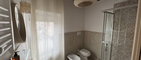 Un baño con ducha, bidé, inodoro y lavabo.