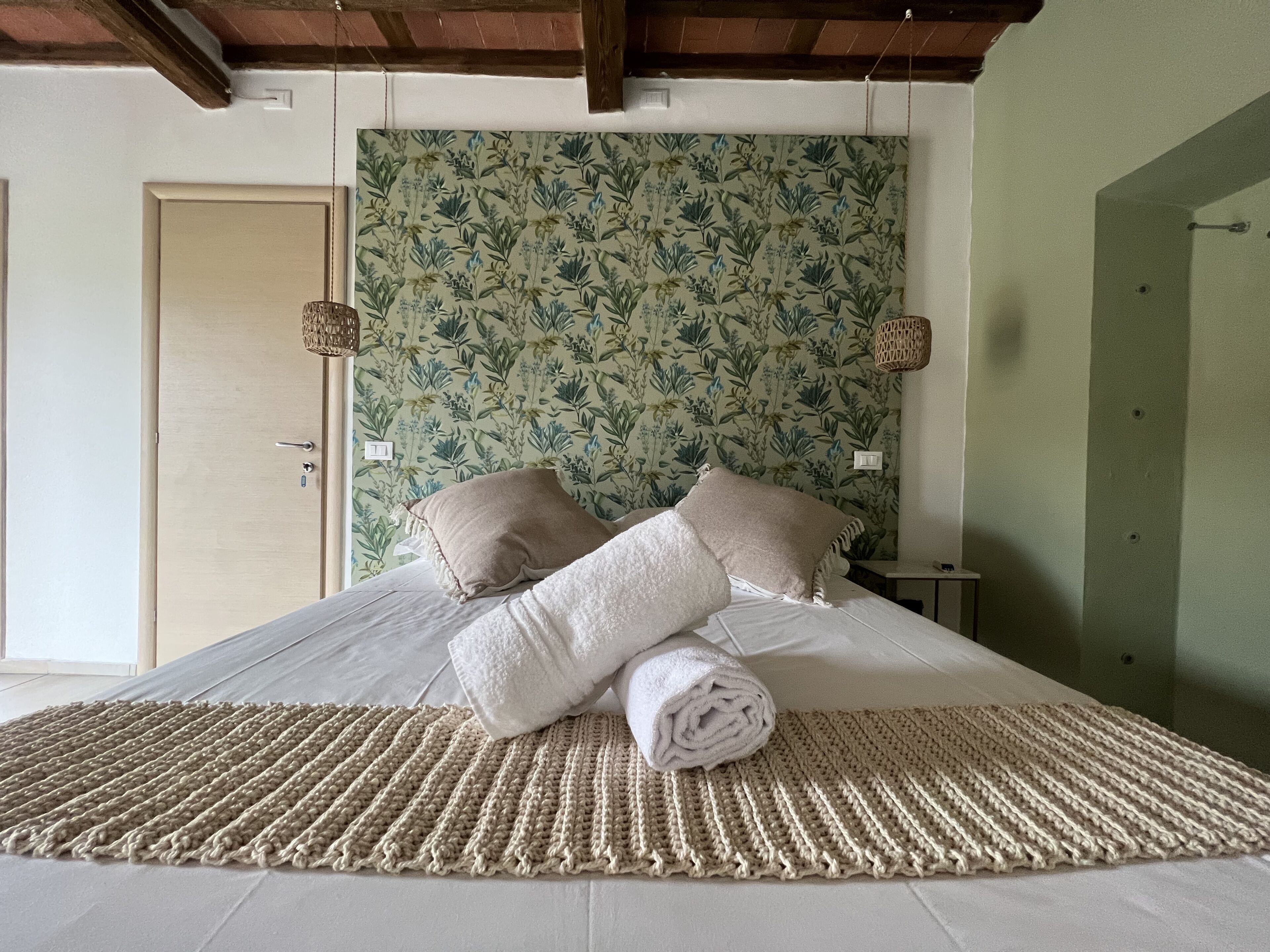 Un dormitorio con una cama grande, papel tapiz floral y una alfombra tejida.