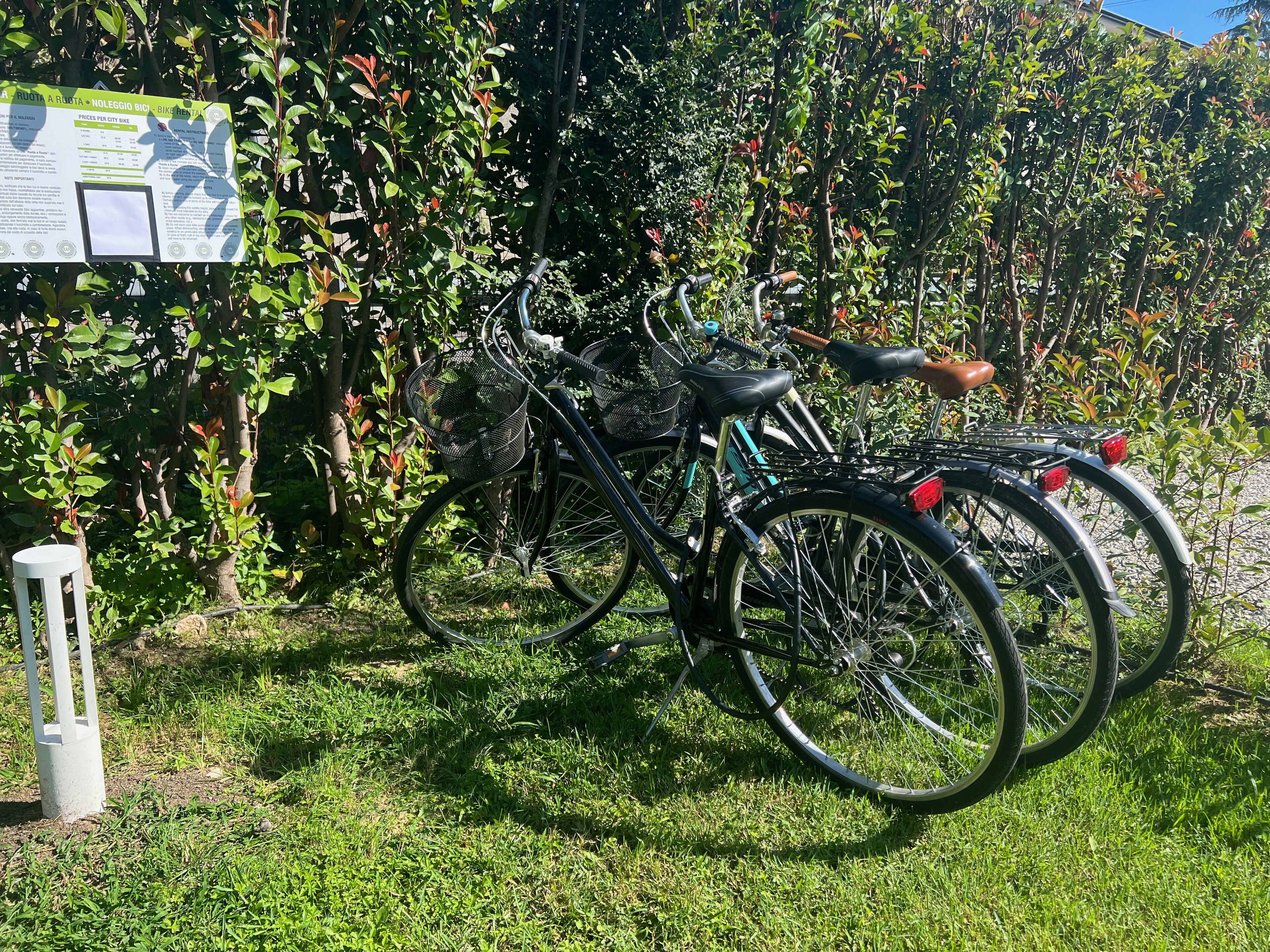 A bicycle parked in a grassy area with a sign in the background.