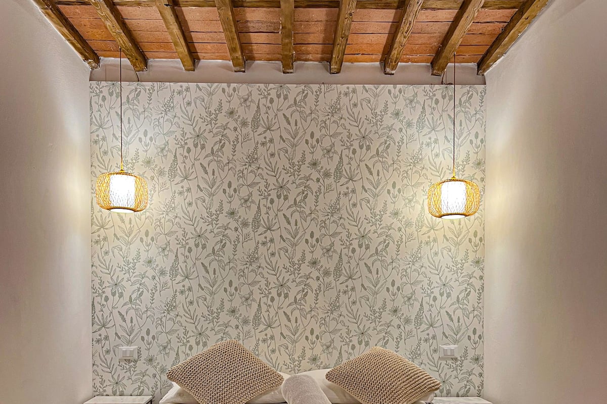 A bedroom with a bed, two bedside tables, and a wooden ceiling.