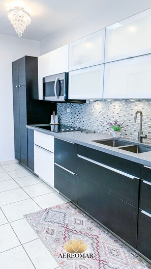 Cocina moderna con microondas, lavamanos y un salpicadero decorativo.