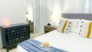 A hotel room with a bed, bedside tables, a dresser, and a mirror. - Modern Chic home close to airport and beach (Carolina)
