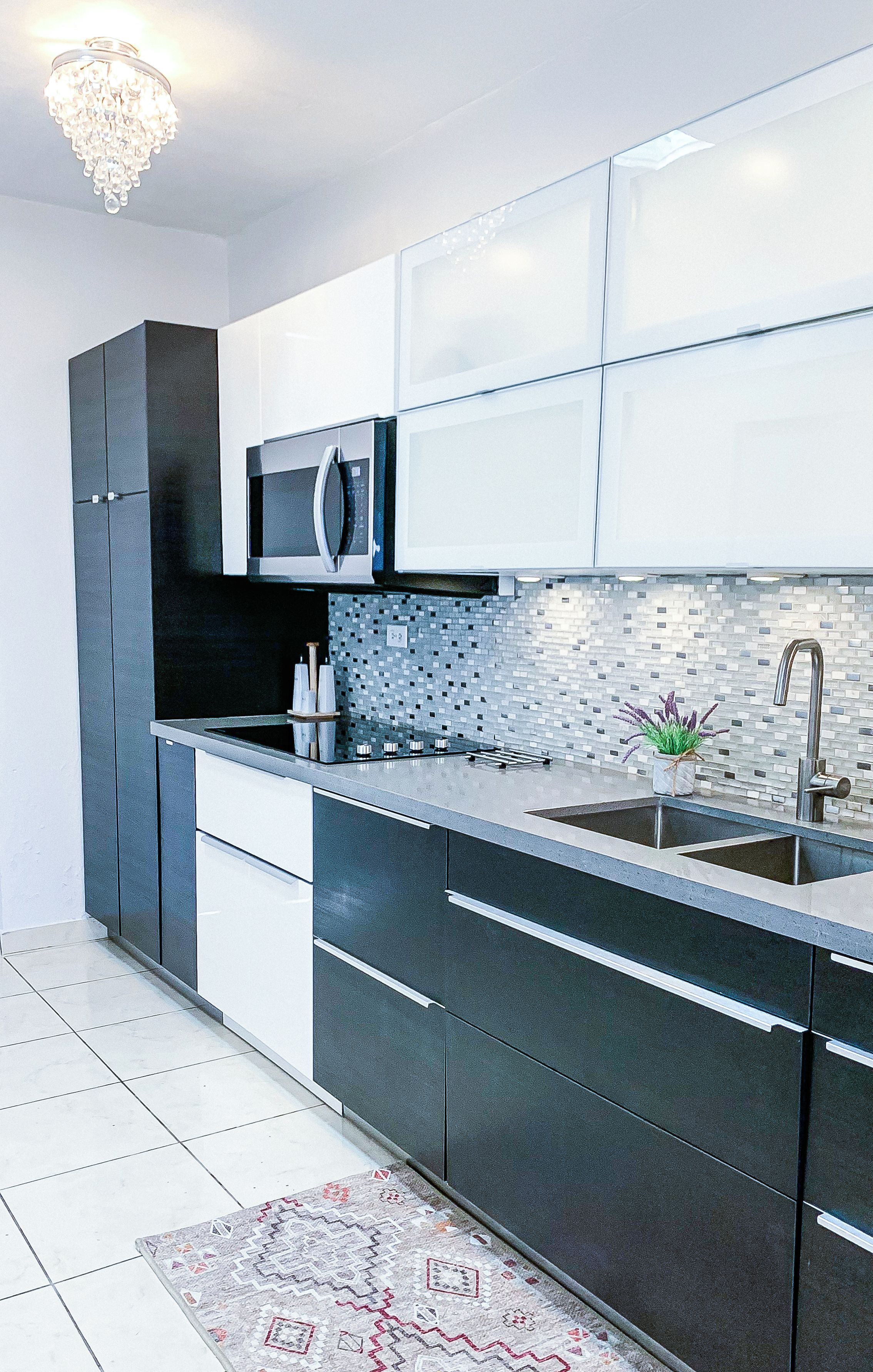 A modern kitchen with dark cabinetry, a stainless steel sink, and a microwave.