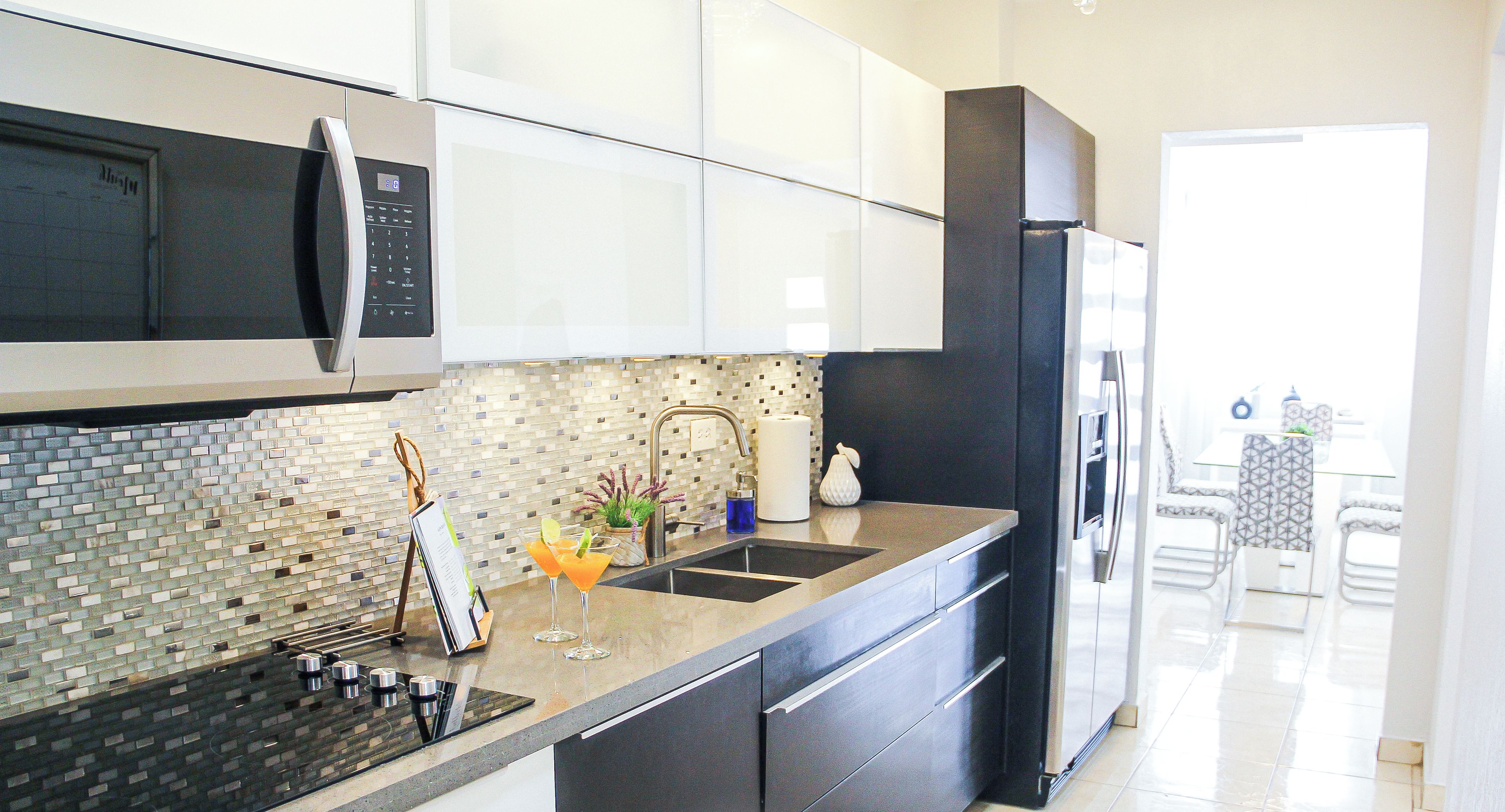Una cocina moderna con un refrigerador negro, electrodomésticos de acero inoxidable y un salpicadero de azulejos.