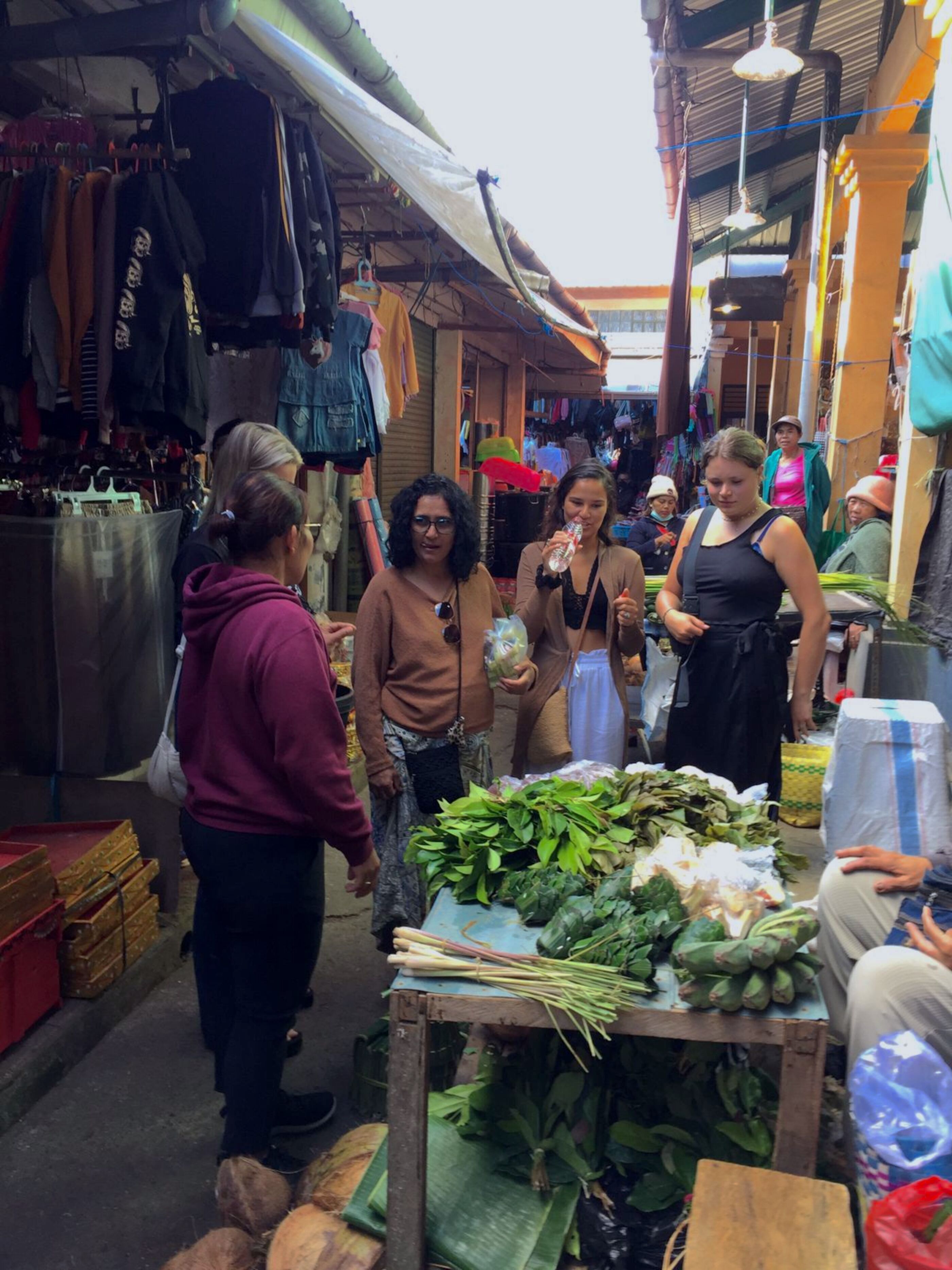 A market with various stalls selling goods, including fresh produce and clothing.