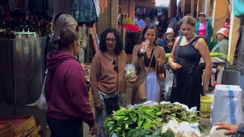A market with various stalls selling goods, including fresh produce and clothing.