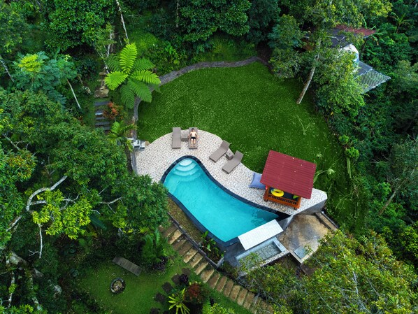 Ein privater Poolbereich mit einer roten Struktur, Liegestühlen und einer kleinen Terrasse.