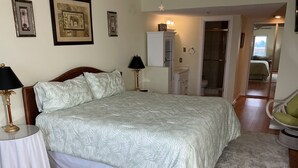 Ein Schlafzimmer mit Bett, Nachttischen, einer Lampe, einem Spiegel und einer Tür zu einem Badezimmer.