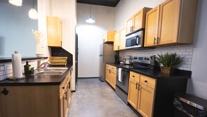 Una cocina moderna con armarios de madera, electrodomésticos de acero inoxidable y encimera negra.
