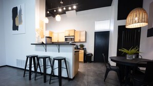 Una cocina moderna con una isla central, taburetes de bar y una mesa de comedor con sillas.