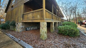 A wooden cabin with a stone foundation, a balcony, and a satellite dish.