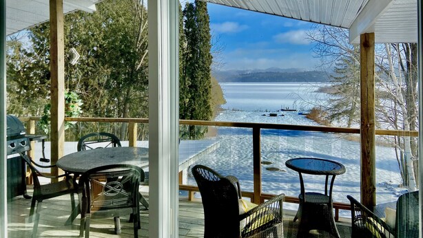 A covered outdoor area with a view of a frozen lake and trees.