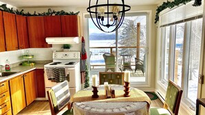 A kitchen with wooden cabinets, a stove, and a dining area with a table and chairs.