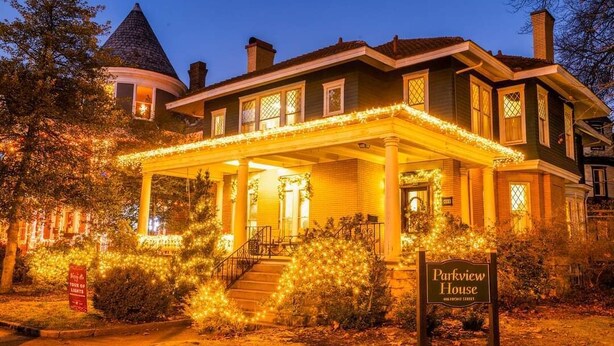 Une maison historique dotée d’un porche couvert, d’une enseigne indiquant « Parkview House », et d’une structure en forme de tourelle en arrière-plan.