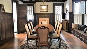 Une salle à manger avec une table et des chaises en bois, un lustre et un tapis à motifs.