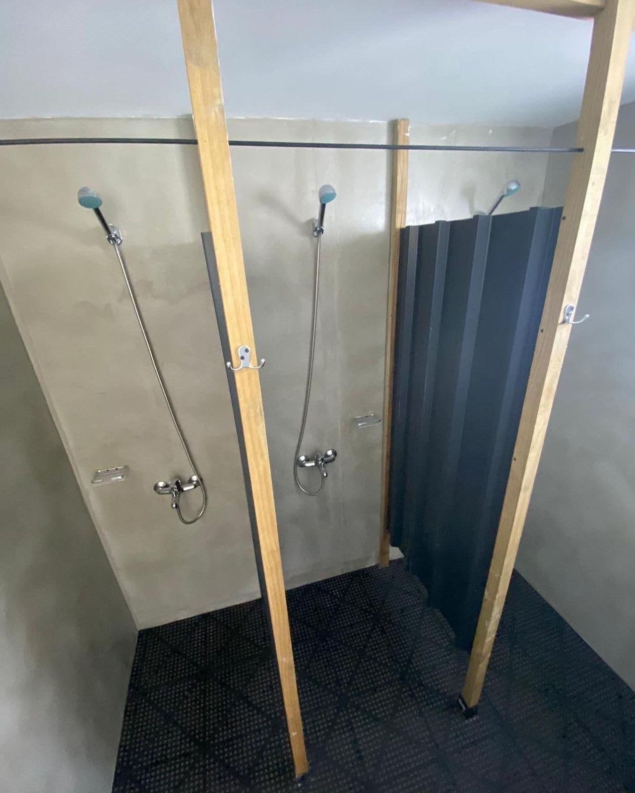 Une petite salle de bain fermée, comprenant un espace douche, des toilettes et un lavabo.