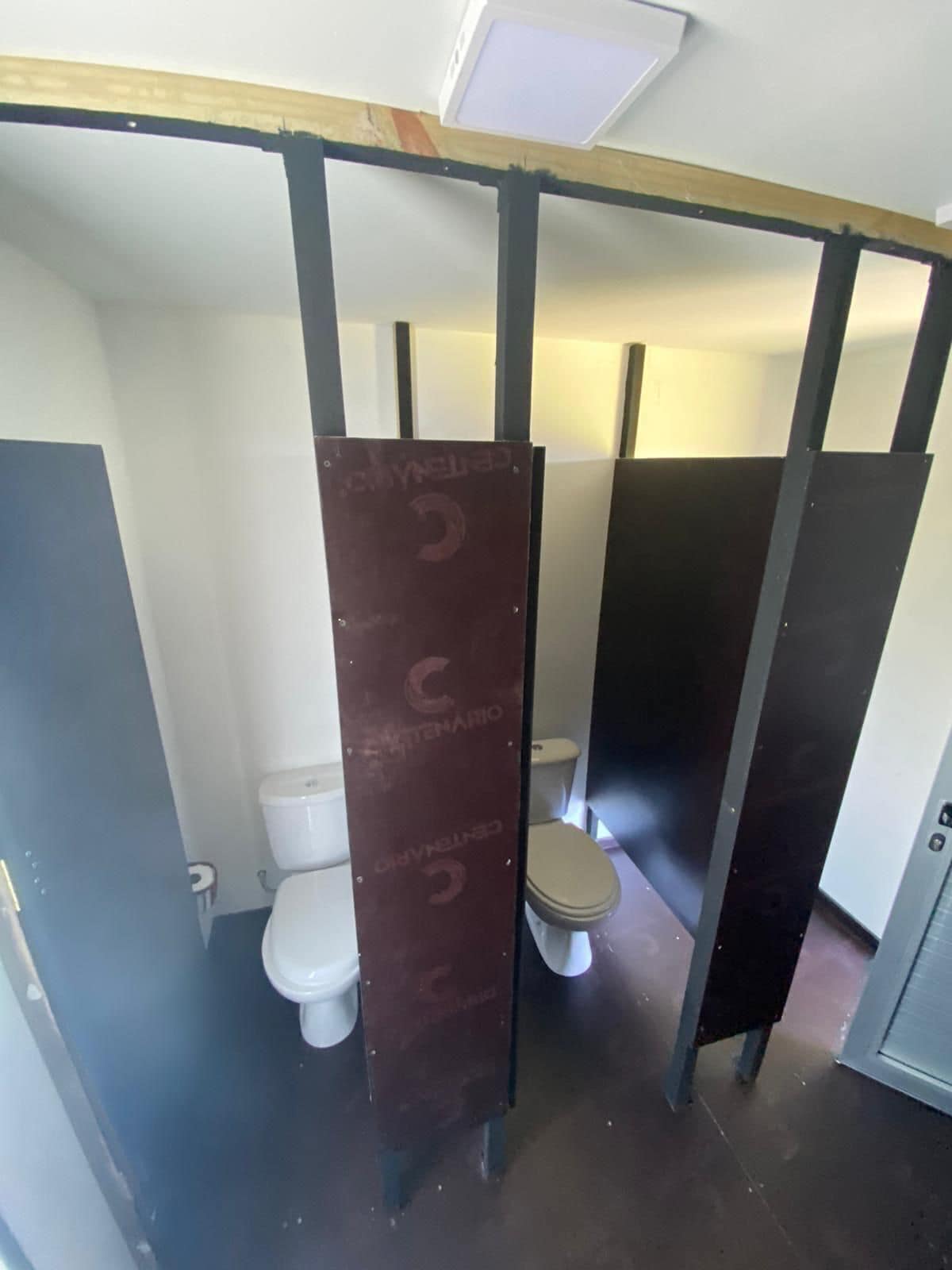 Baño con un inodoro y una pared divisoria con un logotipo.