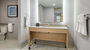 Een moderne badkamer met een houten wastafelmeubel, een grote spiegel en een toilet.