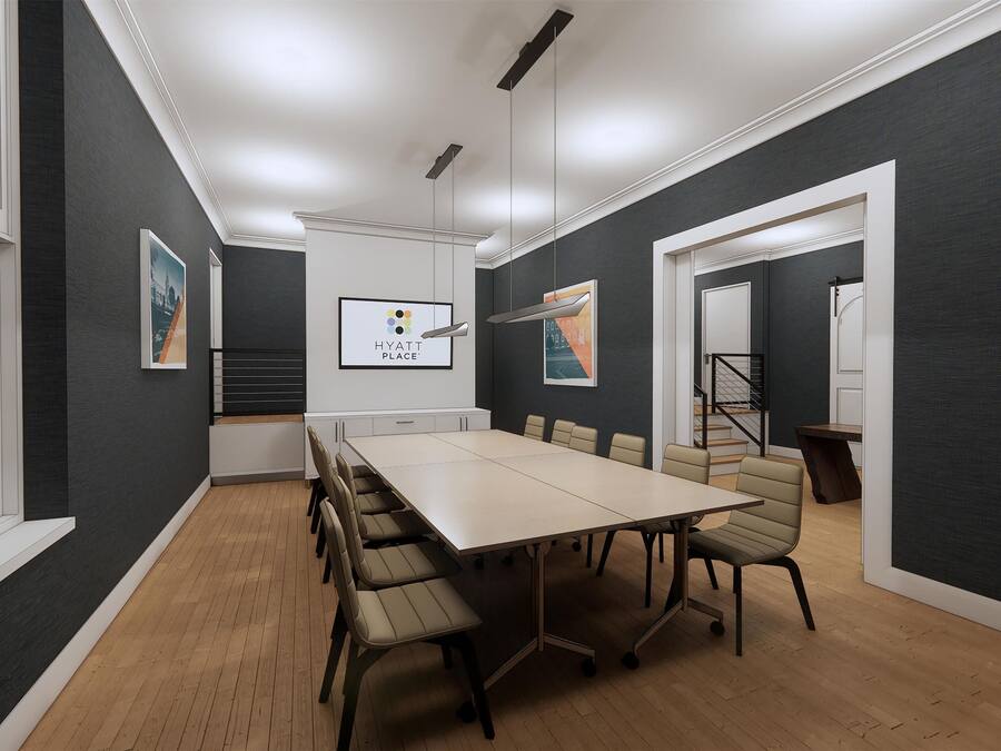 A modern conference room with a long table, chairs, and a staircase in the background.