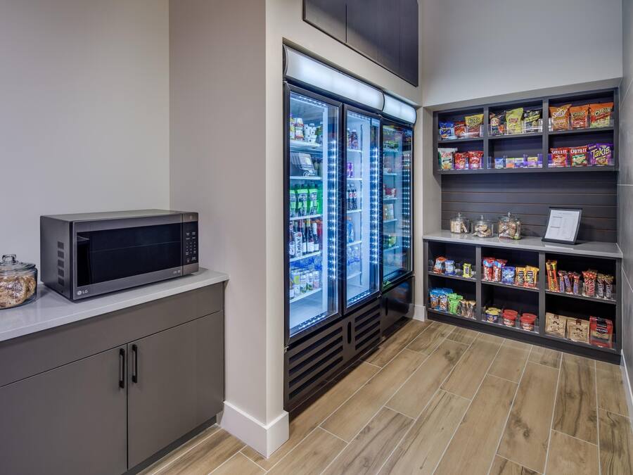 Una kitchenette equipada con microondas, refrigerador y estantes llenos de aperitivos y condimentos.